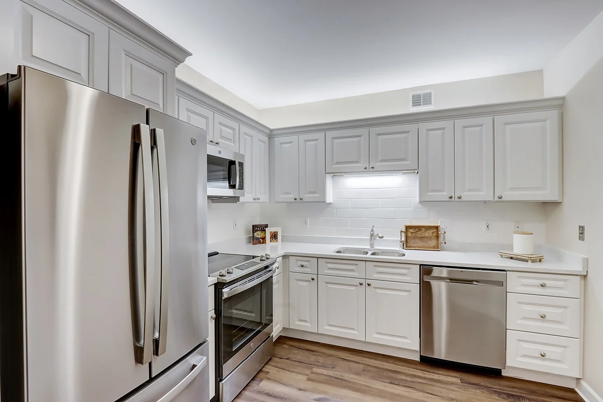 spacious, all-white kitchen with stainless steel appliances in a senior apartment at Newcastle Place Senior Living Community
