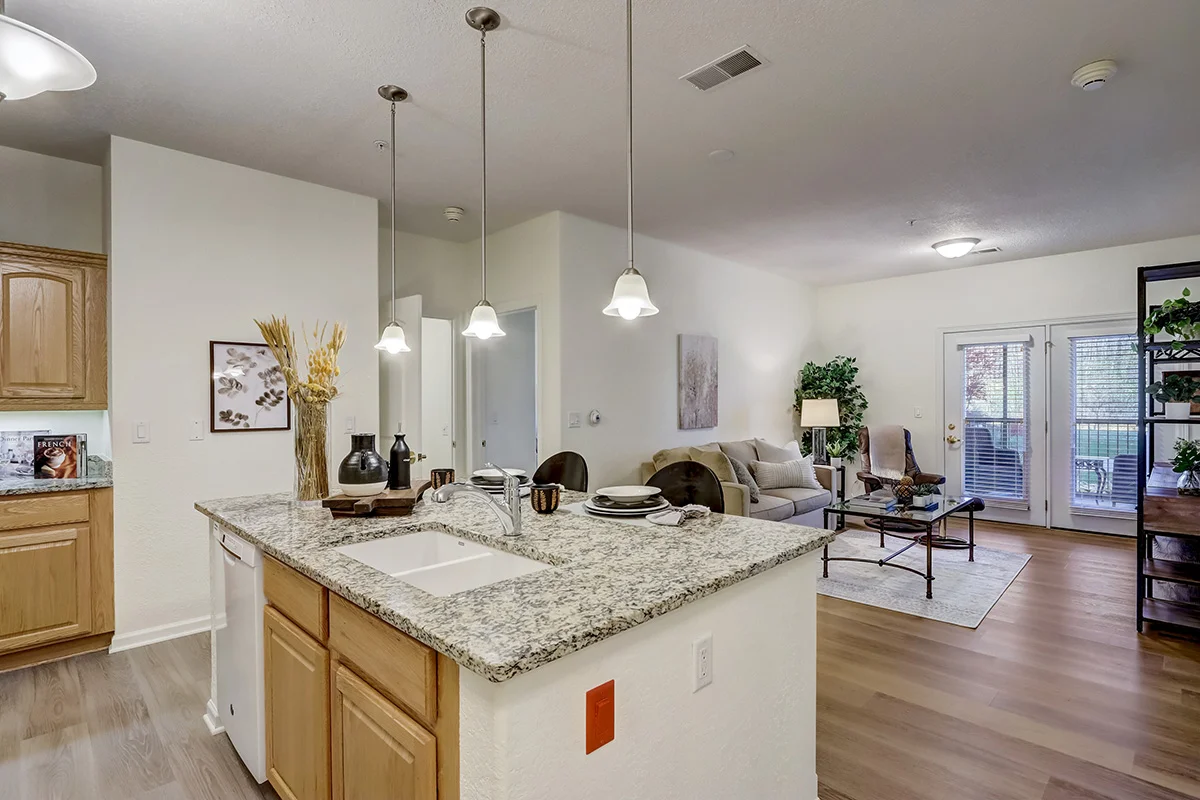 open-concept kitchen with island and fully-furnished living room area in apartment at Newcastle Place Senior Living Community