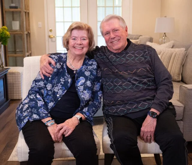 smiling senior couple, Ann and Ed Agnew, sit side-by-side for an interview at Newcastle Place Senior Living Community