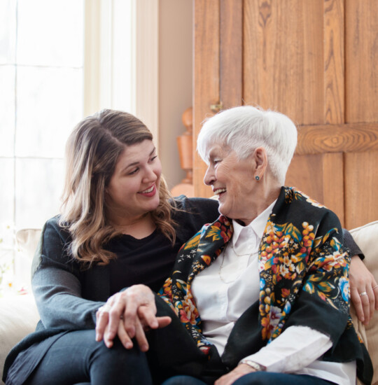 older woman and younger woman on sofa looking at each othwr