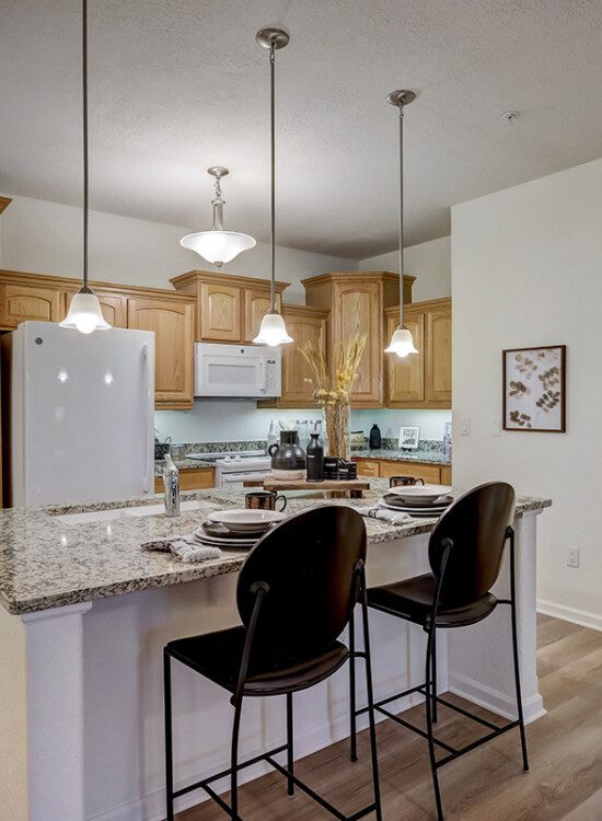 open-concept kitchen featuring a marbled island with hanging pendant lights in an apartment at Newcastle Place Senior Living Community