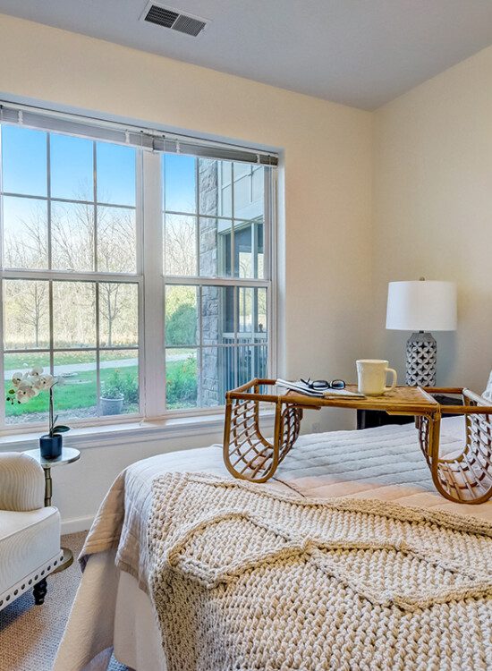 cozy, fully-furnished bedroom with chair in a senior living apartment at Newcastle Place Senior Living Community