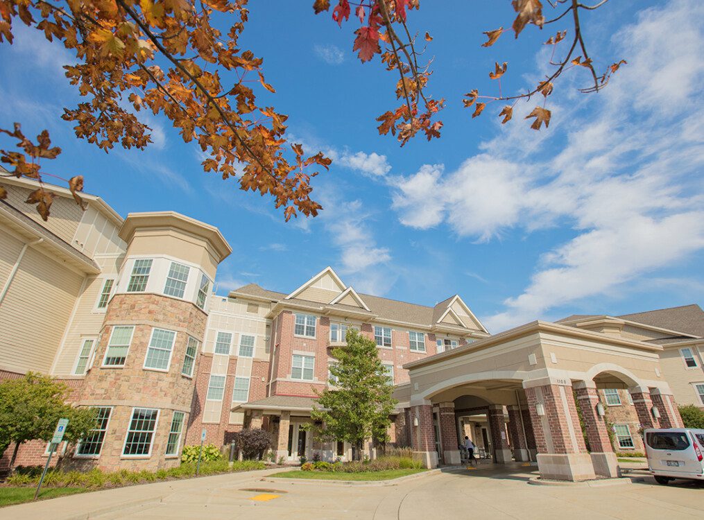 view of the front entrance and driveway at Newcastle Place Senior Living Community in Mequon, WI and fall foliage