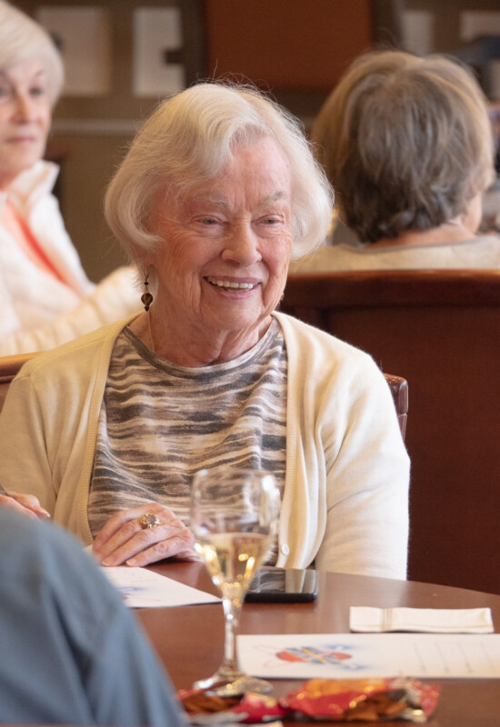 multiple tables of senior friends enjoy snacks and wine during a game night event at Newcastle Place Senior Living Community